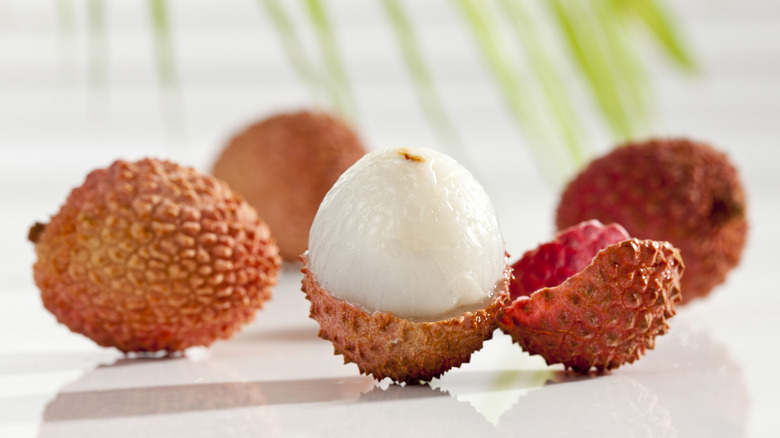 A few lychees surrounded by a peeled lychee