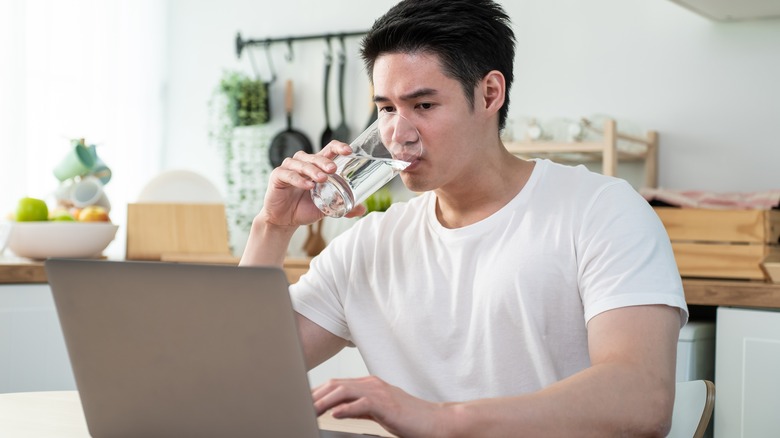 man working and drinking water in kitchen area