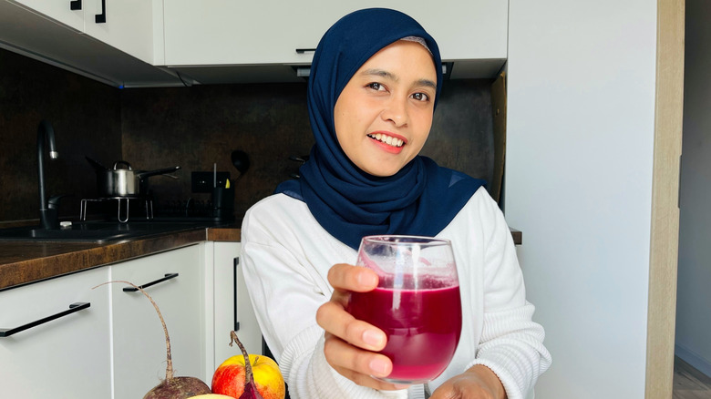 A woman offering her glass of beetroot juice