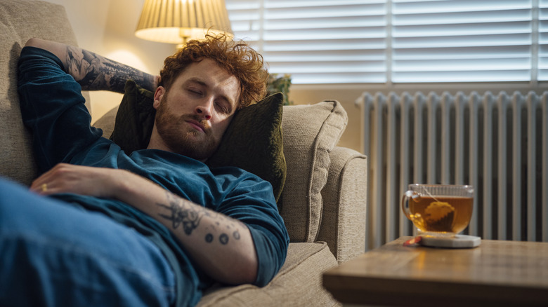 man sleeping on sofa with tea cup near