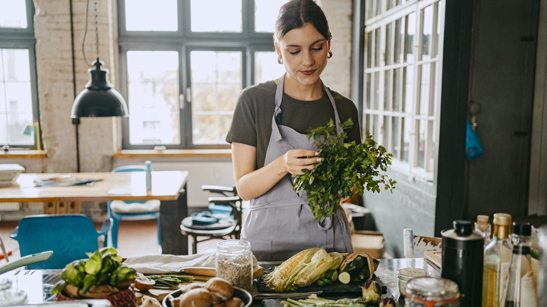 A woman pulling off herbs to put onto her pan roast