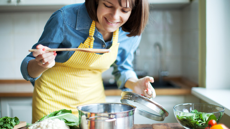 woman making soup with many vegetables