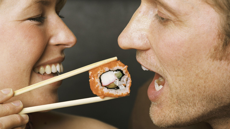 woman feeding man sushi roll