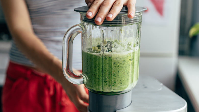 woman blending a green smoothie 