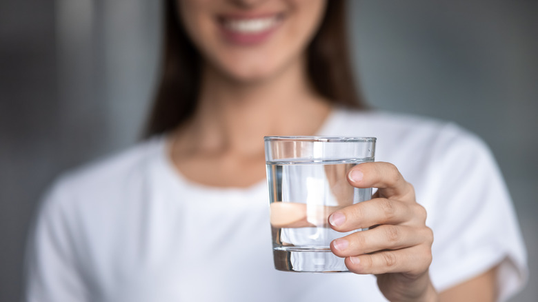 a woman smiling and holding up a glass of water 