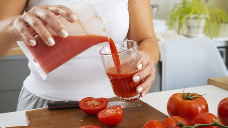 woman pouring a glass of fresh tomato juice