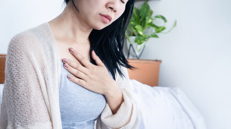 A woman holds her hand to her chest