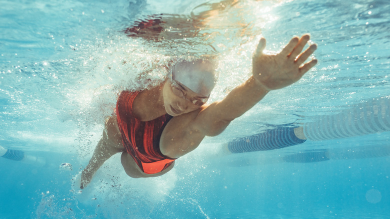 Athlete swimmer with goggles and swim cap swimming under water in their lane