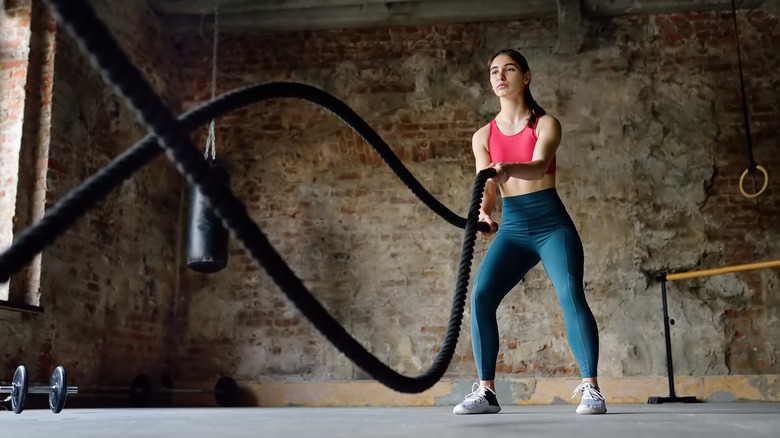 woman exercises with battle ropes 