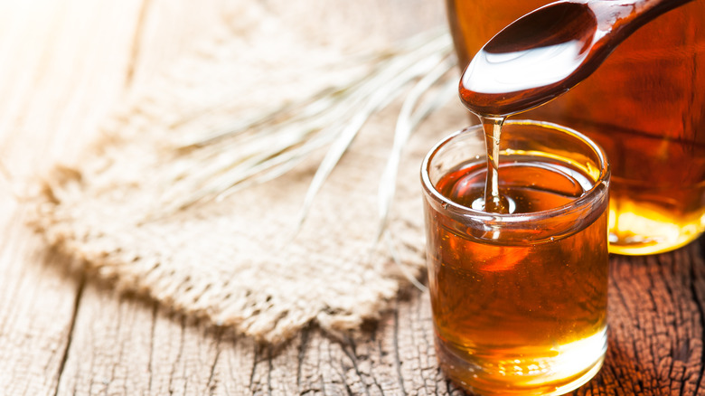 Maple syrup in glass on wooden table