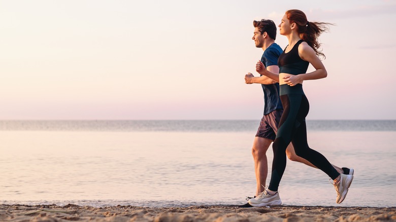 Two people run on the beach