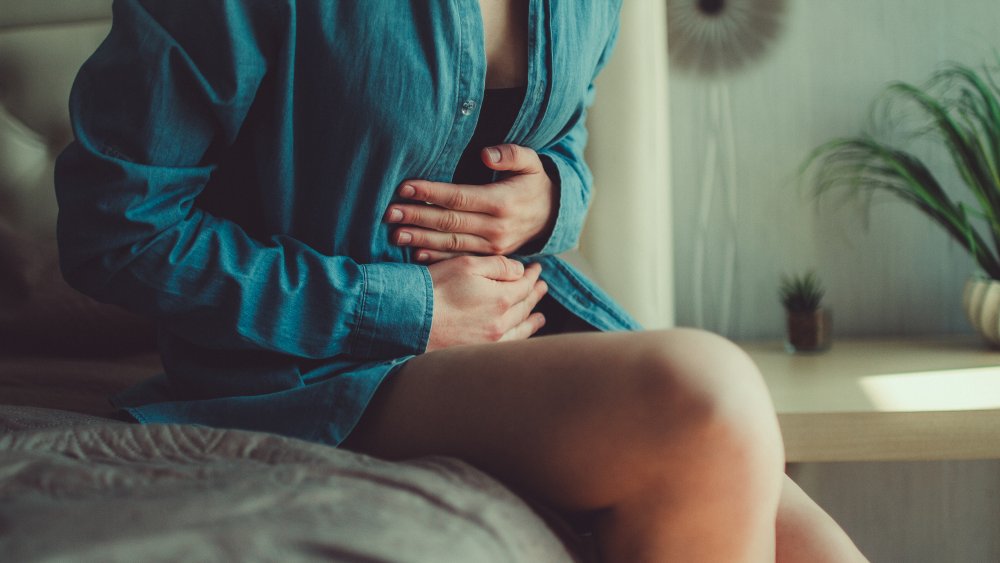 woman with upset stomach, one of the unexpected effects your breakup can have on your body