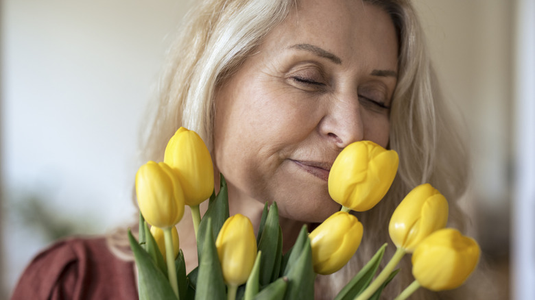 Une femme plus âgée appréciant l’odeur des fleurs