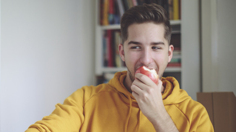 man eating an apple while sitting at his desk