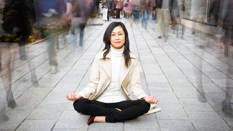 woman sitting calmly on a busy sidewalk