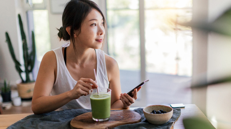 woman drinking a green juice at home