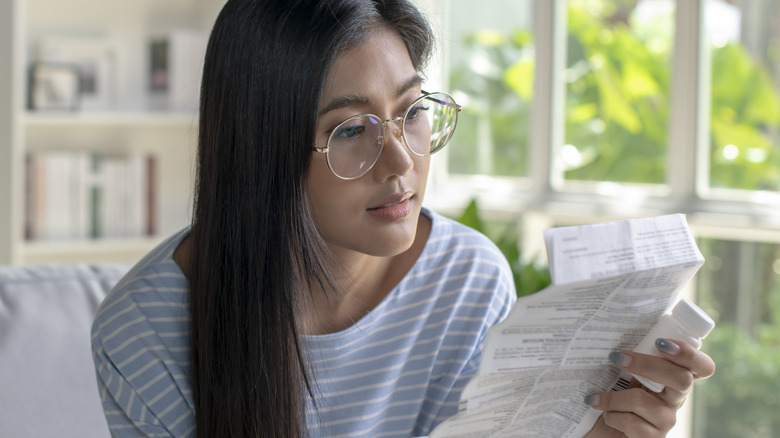 woman holding pill bottle and drug information sheet