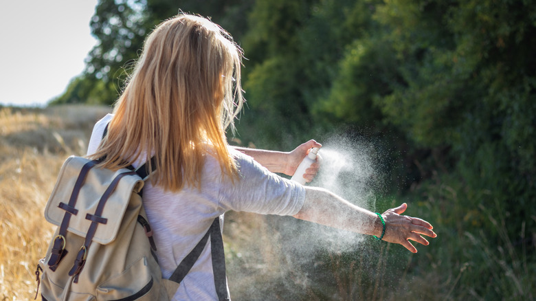 Girl spraying arms for mosquitoes