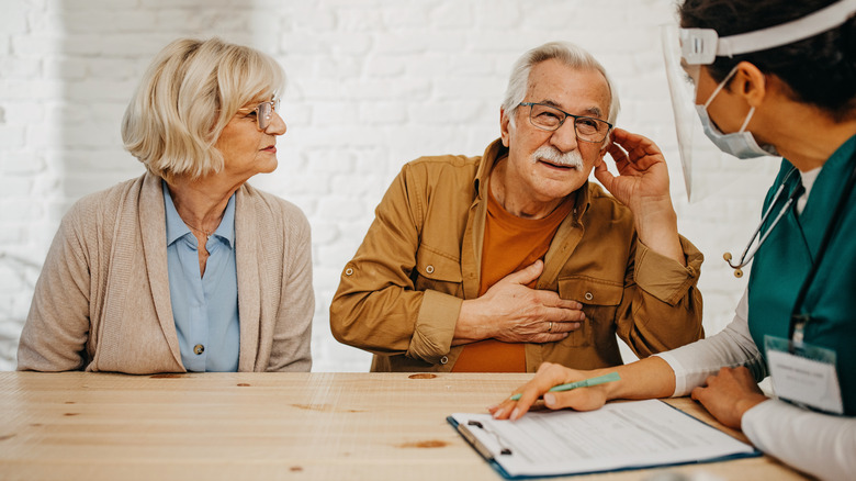 senior couple talking with health worker