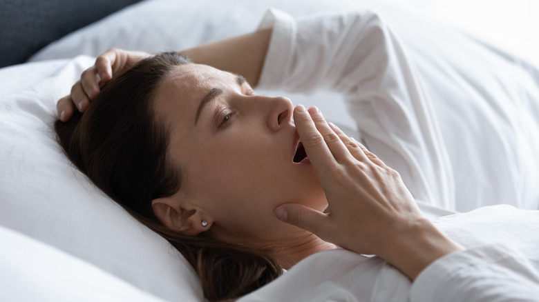 Sleepy woman covering mouth