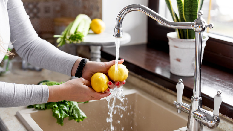 woman washing lemons in sink