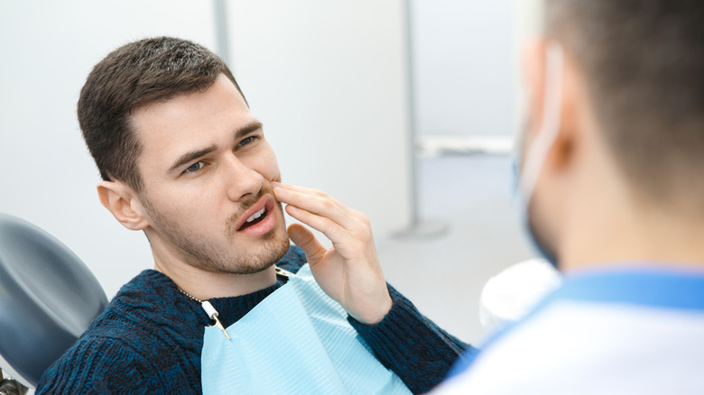 man with toothache sitting in dentist chair