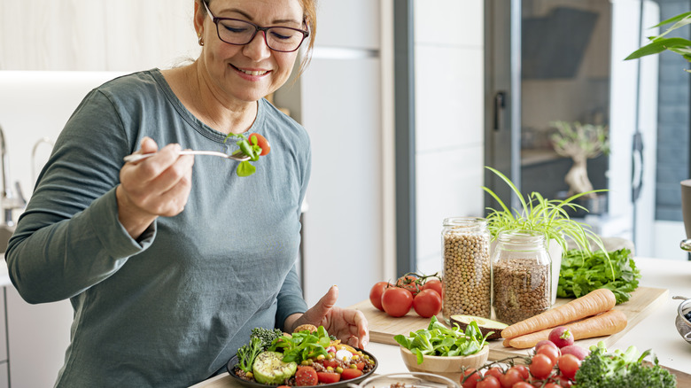 middle-aged woman eating vegetables and grains