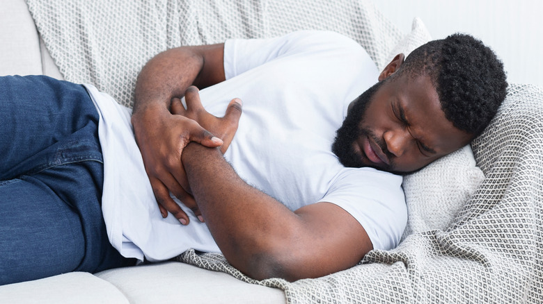 man on a couch holding his stomach