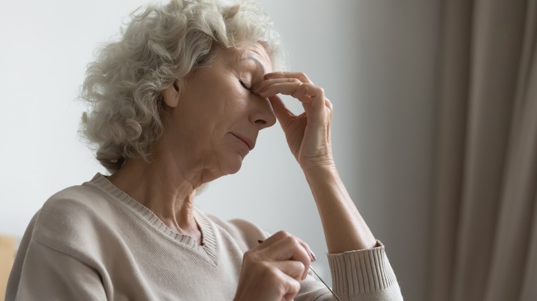 Woman with closed eyes touching the bridge of her nose