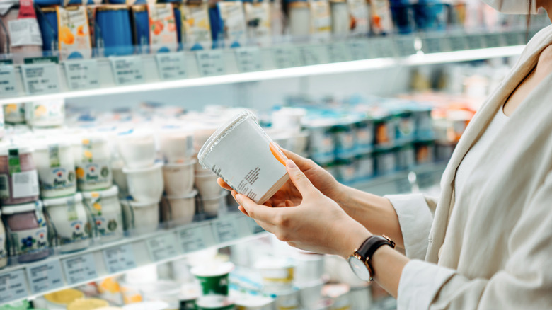 hands holding yogurt in store