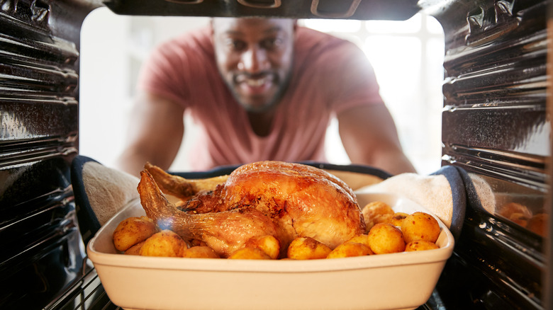 man cooking chicken in oven