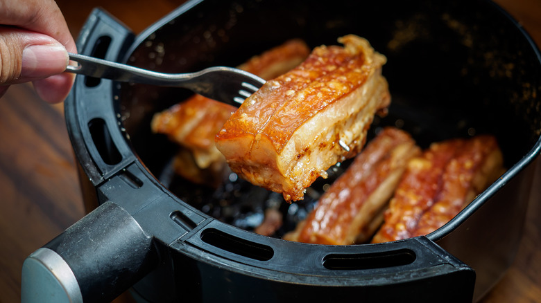 Someone cooks crispy pork in an air fryer