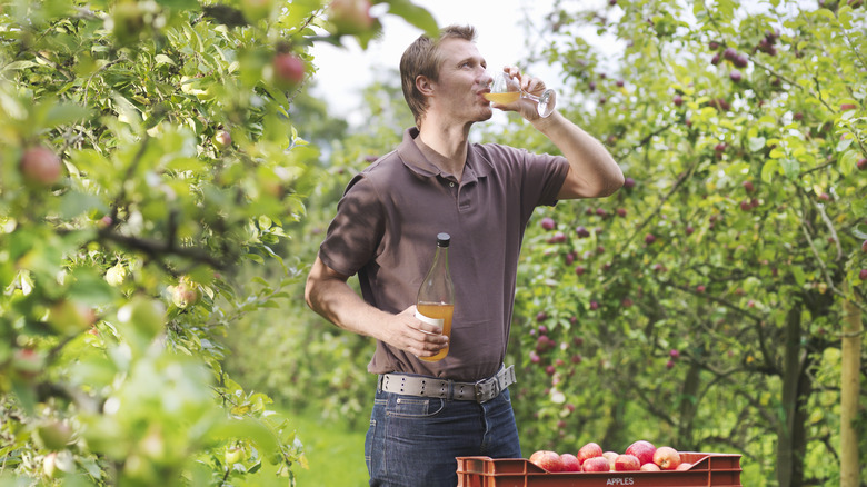 A man drinking apple juice from a wine glass outdoors