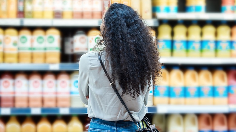 A woman standing in front of shelves of juice