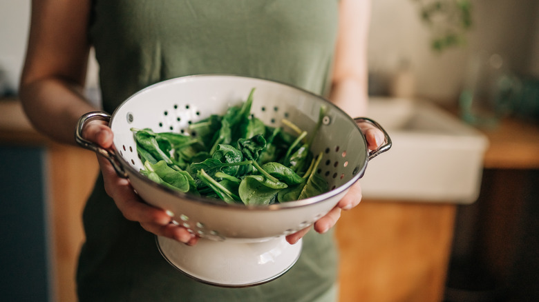 woman's hands holding a bowl of leafy greens