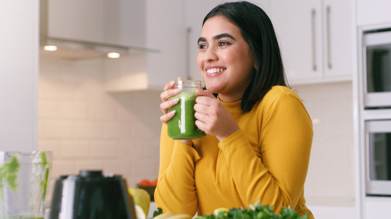 woman drinking a green smoothie