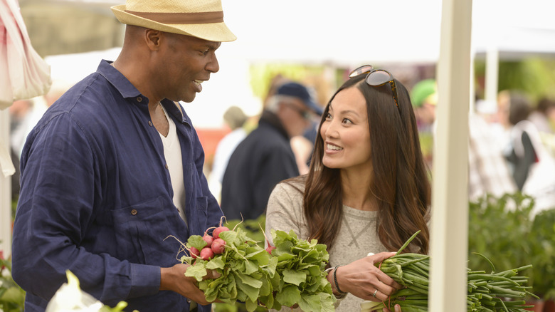 man holding radishes with woman in outdoor market