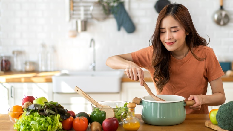 young woman cooking stew on stove in kitchen