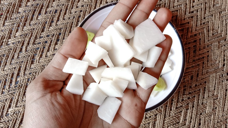 man's hand holding diced turnips