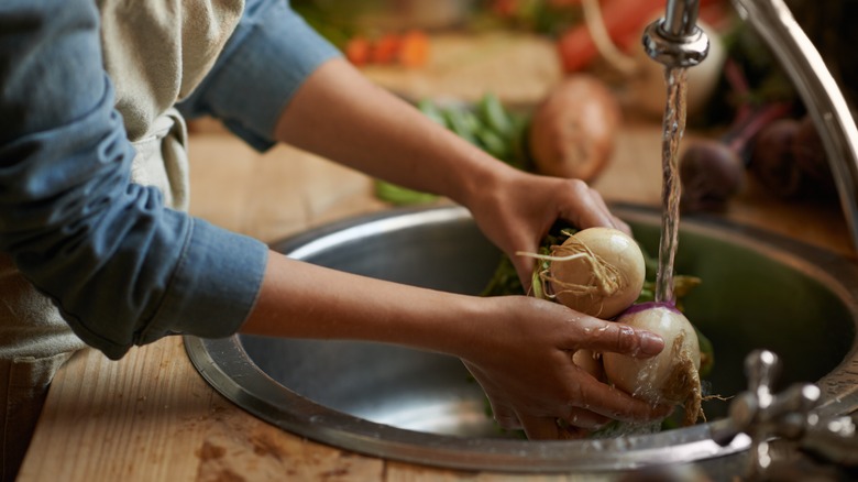 woman cleaning turnips in sink