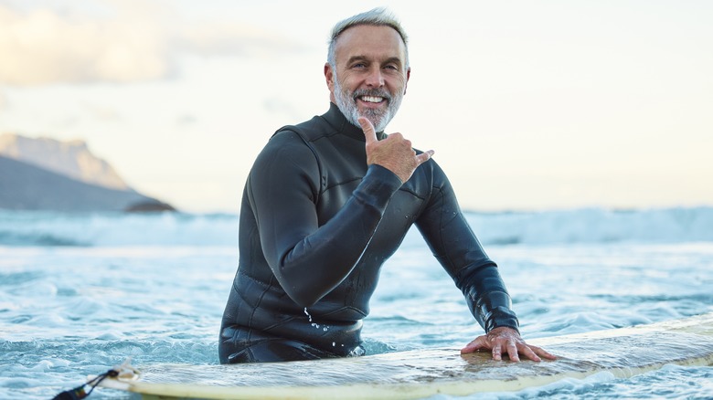 older man in water with surfboard