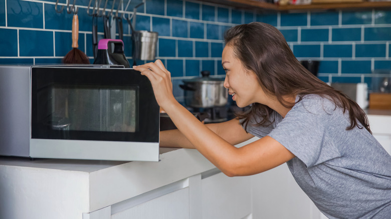 woman reaching into a microwave