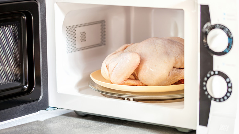 whole, raw chicken in an open microwave