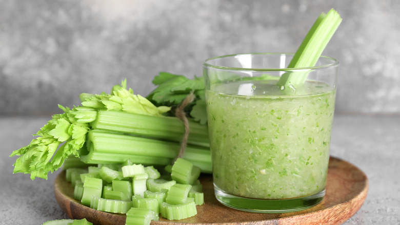 A glass of celery juice next to celery stalks