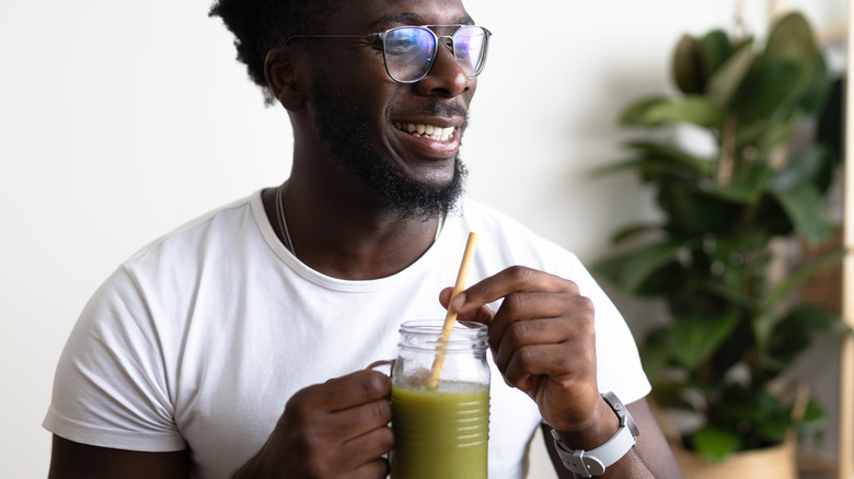 A healthy man drinking a green juice