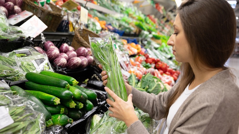 a woman looking through vegetables in the produce section