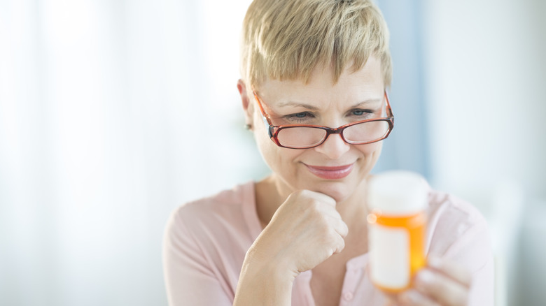 woman looking at the label of her medication