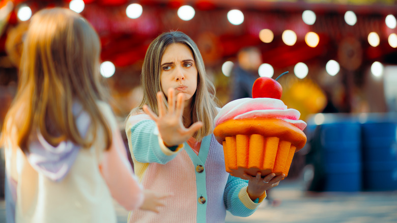 mother pushing away sugary foods from child