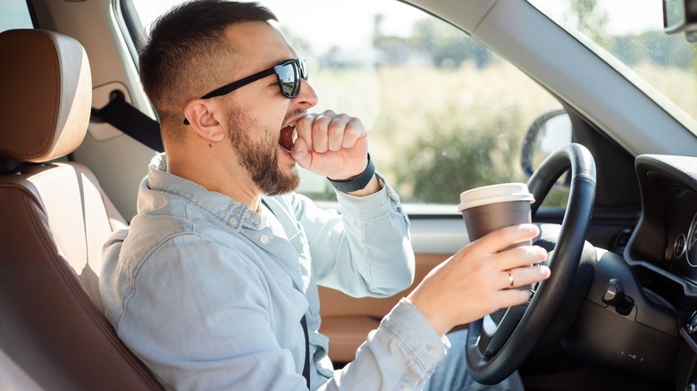 tired man yawning while driving car