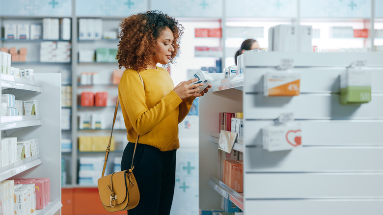 Woman inspecting product on pharmacy shelf